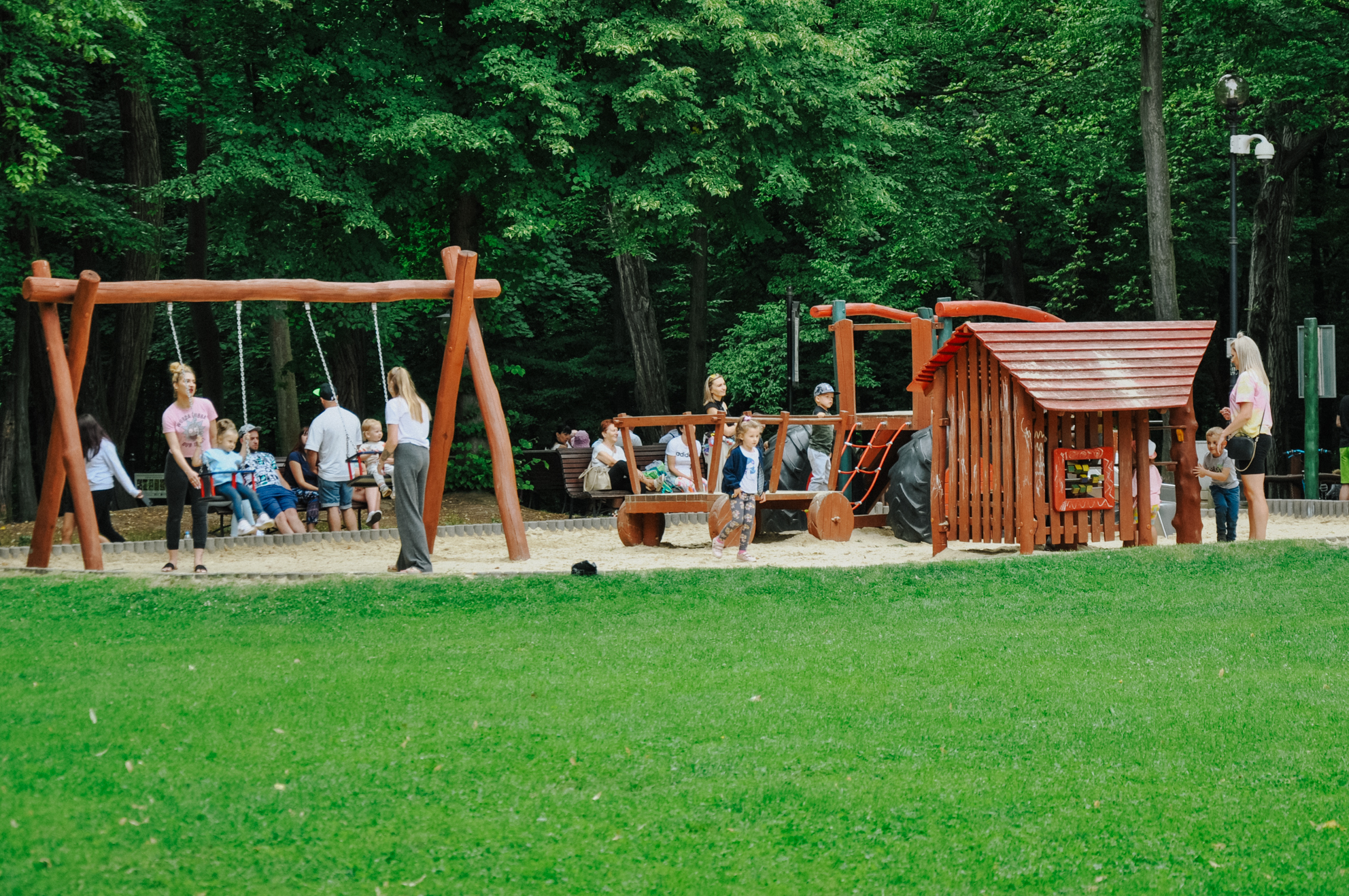 Duży plac zabaw dla dzieci. Jego część znajduje się między drzewami, osłaniając tym samym dzieci od upału 
